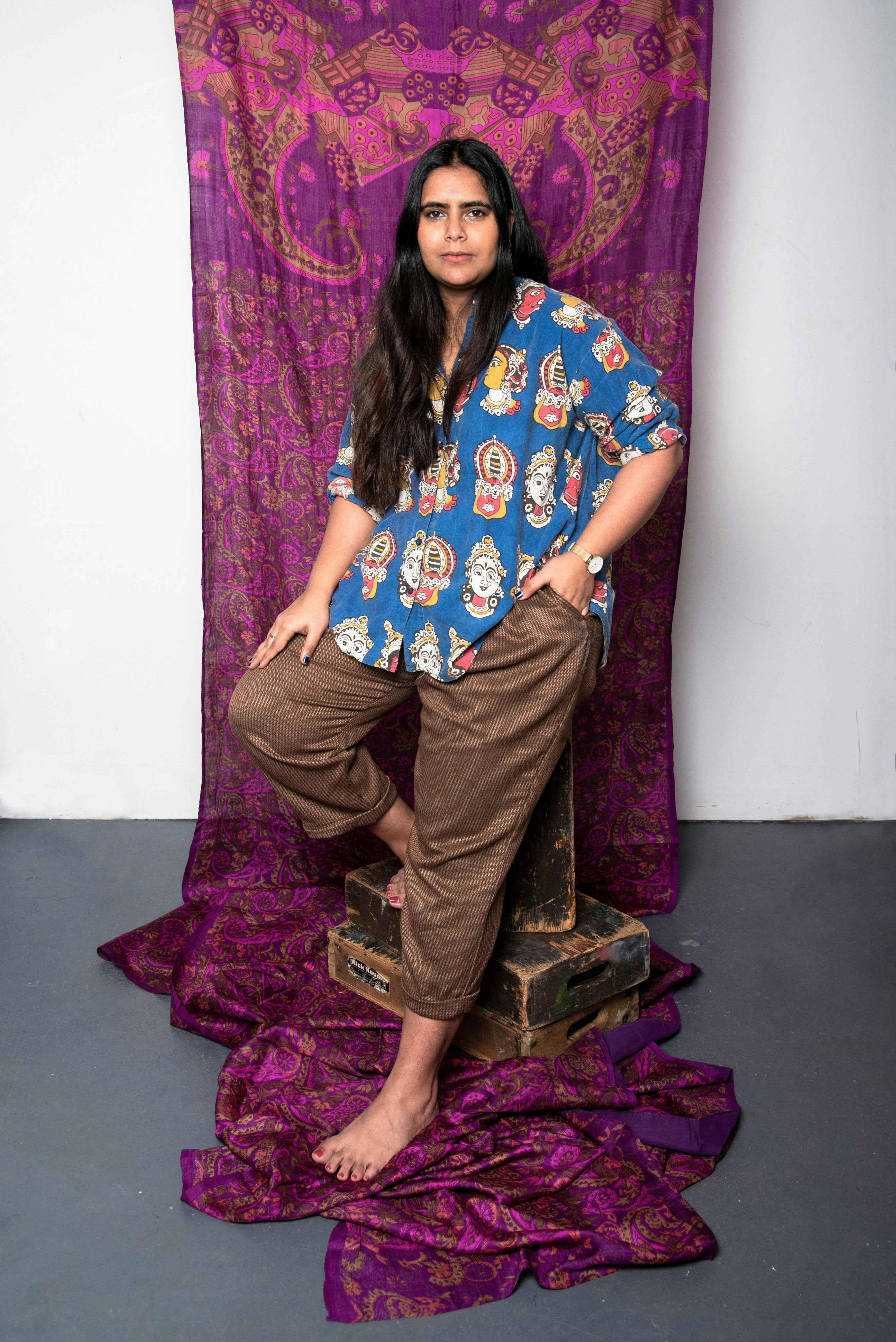 Photo of the artist Spandita Malik posing with hanging fabric