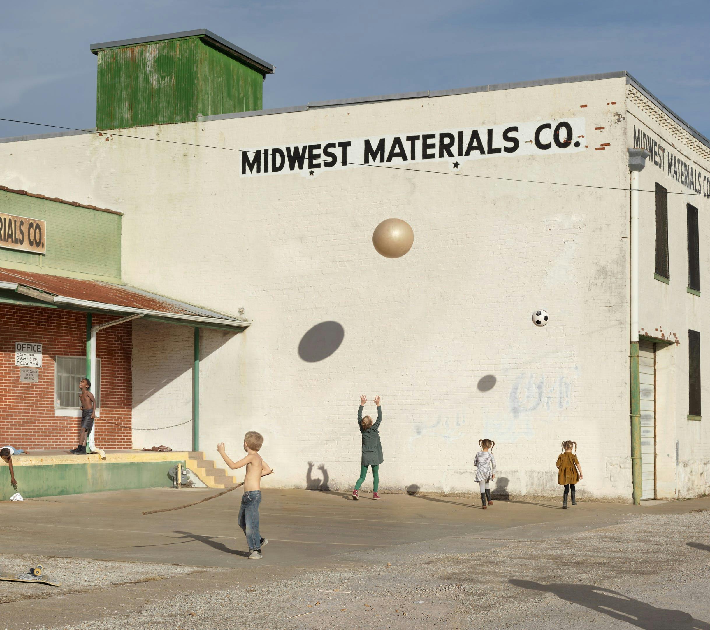 Photography by artist Julie Blackmon of children playing in a parking lot.